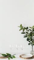 A table with a vase of green leaves and four wine glasses photo