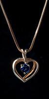 Heart-shaped pendant necklace with a single sapphire photo