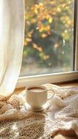 acogedor otoño Mañana con un taza de café por el ventana, calentar luz de sol y de punto cobija foto