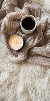 A white blanket with a cup of coffee and a candle on it photo