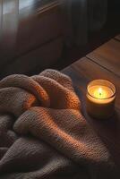 Cozy Warmth of a Candlelit Evening with Soft Knit Blanket on Wooden Table in Tranquil Home Setting photo