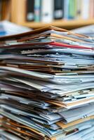 A towering stack of various documents and folders on a desk photo