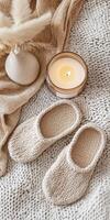 Cozy Hygge Scene with Knitted Slippers, Candle, and Textured Blanket for Relaxation photo