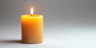 Warm Glow of a Single Lit Candle Against a Soft Gray Background photo