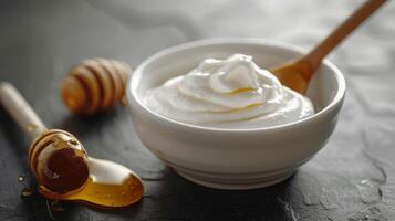 A bowl of yogurt with a spoon and a jar of honey photo