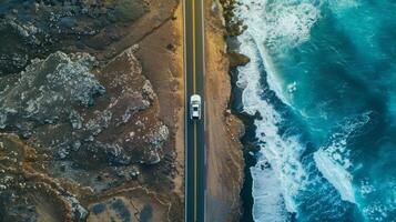 A white car is driving down a road that is next to a body of water photo