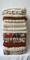 Cozy Stack of Knitted Sweaters in Various Patterns and Textures on a Neutral Background photo