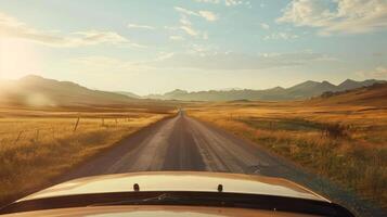 A car is driving down a long, empty road with mountains in the background photo