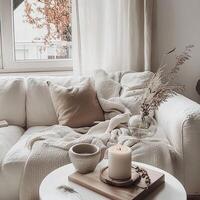 A white couch with a brown pillow and a white blanket on it photo