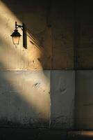 Vintage Street Lamp Casting Shadows on Weathered Wall in Soft Evening Light photo
