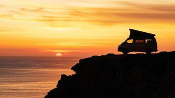 Camper van silhouette on a cliff edge at sunset during a road trip photo