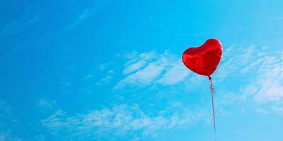 A red heart-shaped balloon floating in a crystal-clear blue sky photo
