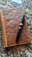 A pen is sitting on top of a leather bound book photo