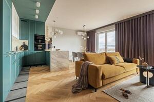 Creative and modern vintage open space interior design with yellow sofa and turquoise kitchen with island. Grey carpet on the herringbone parquet with coffee table, curtain in windows. Template. photo