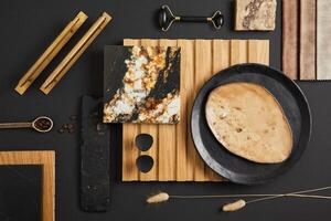 Stylish flat lay comosition of creative architect moodboard with samples of textile, paint, wooden lamella panel and marble tile. Golden, black and beige color palette. Copy space. Template. photo
