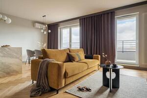 Creative and modern open space interior design with yellow sofa, grey carpet and coffee table . Grey carpet on the herringbone parquet with coffe table, brown curtain in windows. Template. photo
