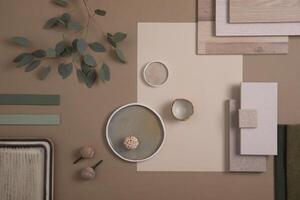 Creative flat lay composition of interior designer moodboard with textile and paint samples, panels and tiles. Beige, brown and green color palette. Copy space. Template. photo