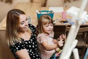 Mother and daughter enjoying a creative painting session indoors together photo
