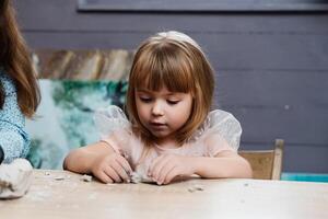 child engaged in creative play with clay at a table indoors photo