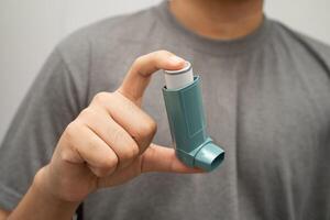 Asthma and chronic obstructive pulmonary disease COPD, Asian young man using metered dose inhaler MDI. photo