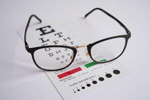 Glasses on eye exam chart to test eyesight accuracy of reading. photo