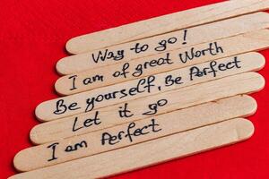 Positive thoughts for increasing self-esteem on wooden posts on red background photo
