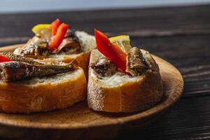 fish sandwich with butter and sprats lemon on a wooden plate, side view close up photo