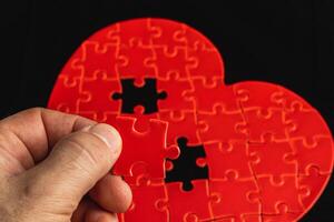 Concept of feelings in a puzzle. Hand puts missing pieces into a heart puzzle photo