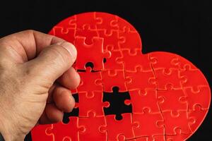 Concept of feelings in a puzzle. Hand puts missing pieces into a heart puzzle photo