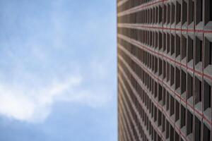 A modern building with a red and black pattern on the facade with blurred blue sky, Close up and selective focus. photo