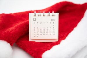 Simple desk calendar for DECEMBER 2024 with Santa hats on white background. New year Calendar concept with copy space. 2024 DEC calendar. photo