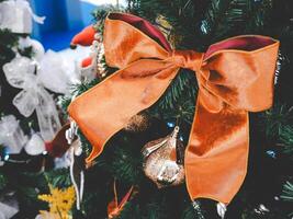 Christmas bow hanging on the Christmas tree. Magic details with twinkling bokeh lights on background. Winter holiday wallpaper. Merry Christmas. Christmas background. photo