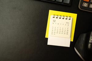 Simple desk calendar for December 2024 on desk with office supplies. Calendar concept with copy space. 2024 DEC calendar. photo