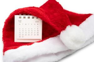 Simple desk calendar for DECEMBER 2024 with Santa hats on white background. New year Calendar concept with copy space. 2024 DEC calendar. photo
