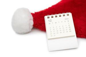 Simple desk calendar for DECEMBER 2024 with Santa hats on white background. New year Calendar concept with copy space. 2024 DEC calendar. photo