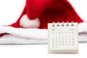 Simple desk calendar for DECEMBER 2024 with Santa hats on white background. New year Calendar concept with copy space. 2024 DEC calendar. photo