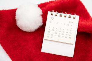 Simple desk calendar for DECEMBER 2024 with Santa hats on white background. New year Calendar concept with copy space. 2024 DEC calendar. photo