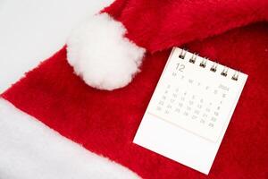 Simple desk calendar for DECEMBER 2024 with Santa hats on white background. New year Calendar concept with copy space. 2024 DEC calendar. photo