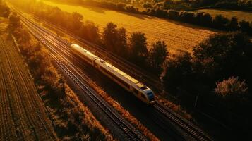 Golden light and long shadows, train travel captured from above. Aerial view train passing through photo