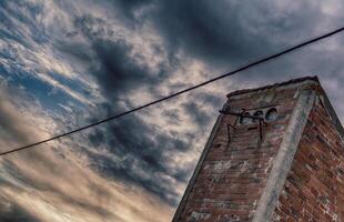 Rustic Brick Chimney Under a Dramatic Cloudy Sky in HDR photo technique