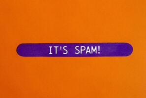 It's spam message written on purple wooden stick with orange background. Conceptual it's spam symbol. Copy space. photo