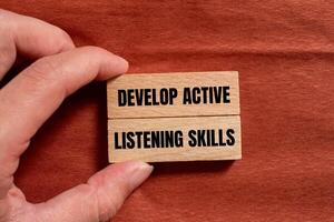 Develop active listening skills message written on wooden blocks with brown background. Conceptual develop active listening skills symbol. Copy space. photo