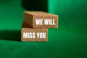 We will miss you message written on wooden blocks with green background. Conceptual we will miss you symbol. Copy space. photo