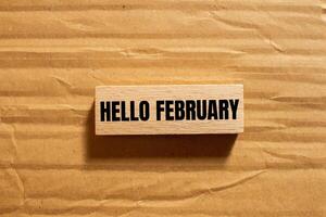 Hello february message written on wooden block with cardboard background. Conceptual hello february symbol. Copy space. photo