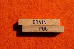 Brain fog message written on wooden blocks with orange background. Conceptual brain fog symbol. Copy space. photo