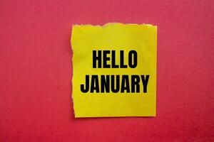 Hello january message written on ripped torn yellow paper piece with red background. Conceptual hello january symbol. Copy space. photo