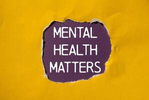 Mental health matters message written on ripped torn yellow paper with purple background. Conceptual mental health matters symbol. Copy space. photo