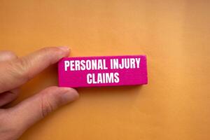 Personal injury claims message written on pink wooden block with orange background. Conceptual personal injury claims symbol. Copy space. photo