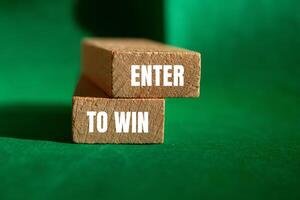 Enter to win message written on wooden blocks with green background. Conceptual enter to win symbol. Copy space. photo