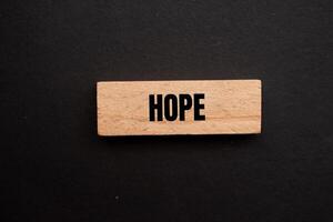 Hope message written on wooden block with black background. Conceptual hope symbol. Copy space. photo